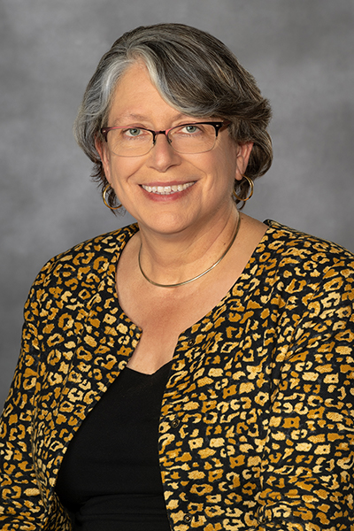 A woman wearing a black and gold blazer with a black blouse.