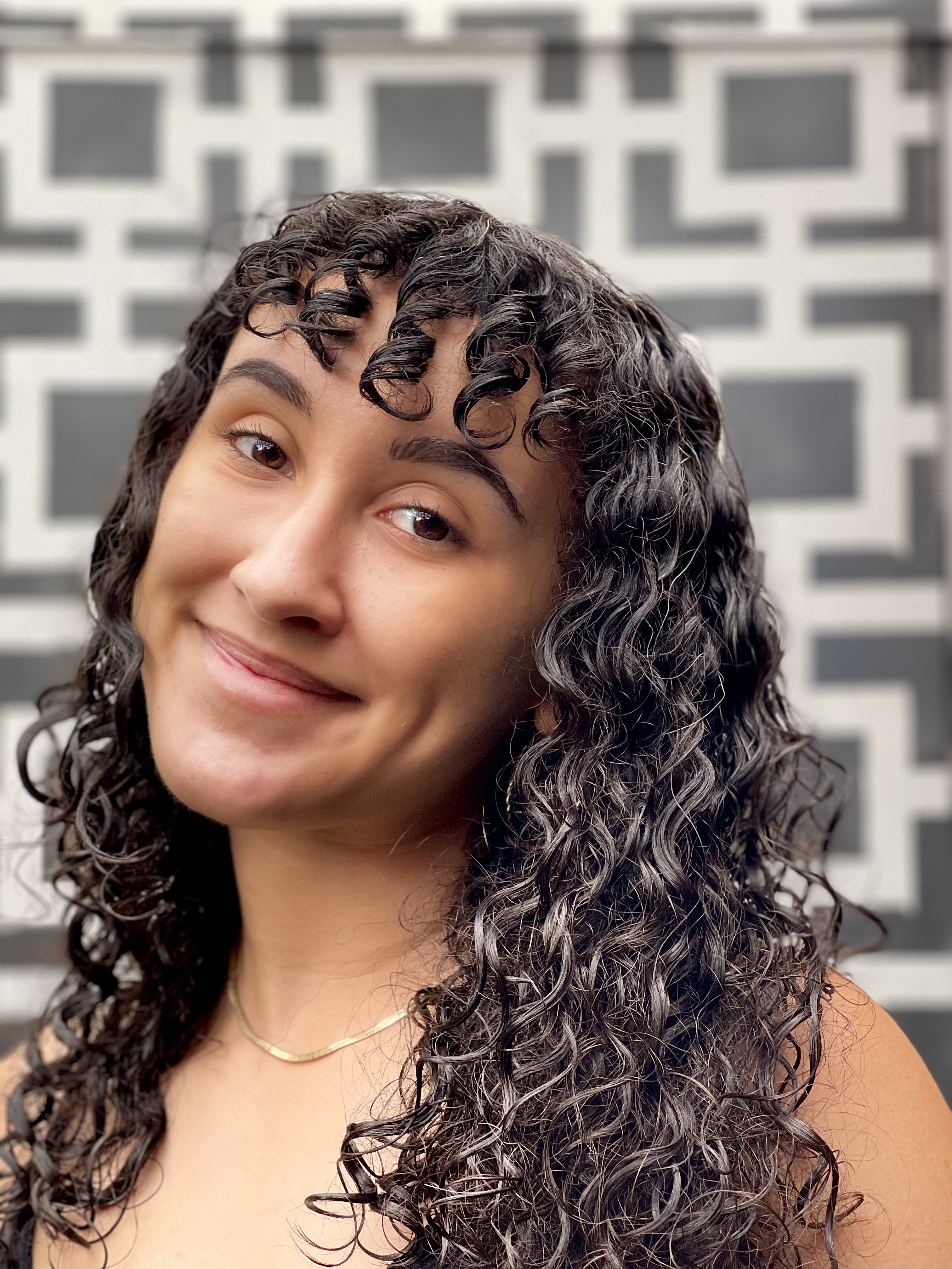 A woman with curly hair stadning in front of a piece of art