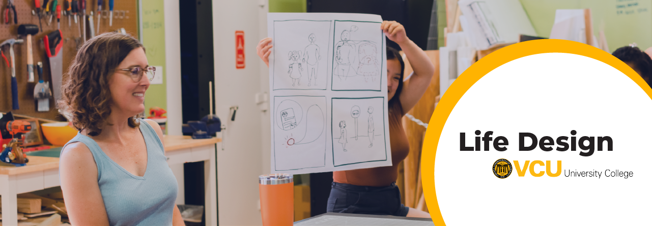 A member of faculty holding a conversation as a student holds up a large poster page with their drawings on it.